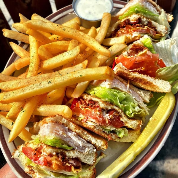 Eat'n Park's club sandwich with crispy fries, a pickle spear, and a side of ranch dressing.