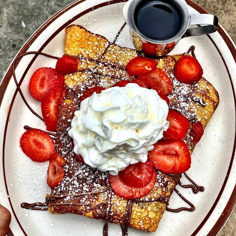 Eat'n Park's French toast with strawberries, whipped cream, chocolate drizzle, and powdered sugar.