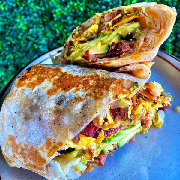 A breakfast burrito from Eat'n Park, cut in half, revealing eggs, bacon, and avocado.