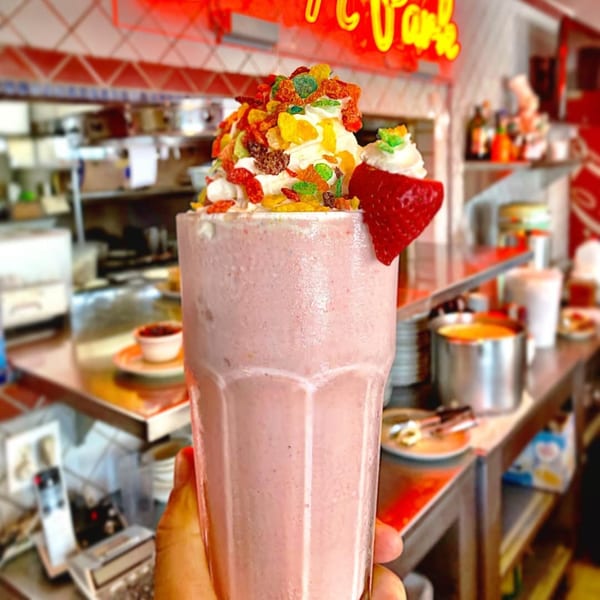 A strawberry milkshake topped with whipped cream, colorful cereal, and a fresh strawberry at Eat'n Park.